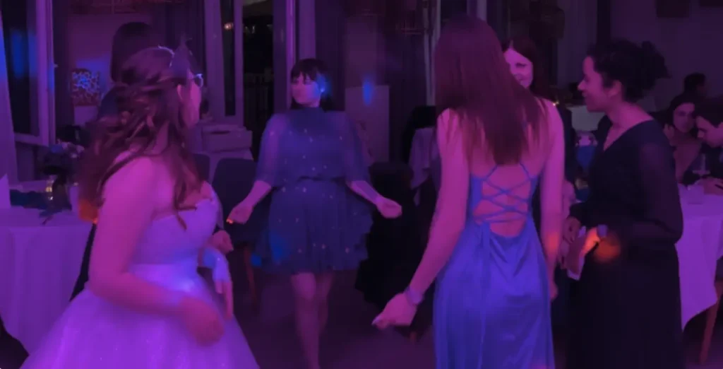 Frauen in Abendkleidern und Brautkleid tanzen auf einer Party